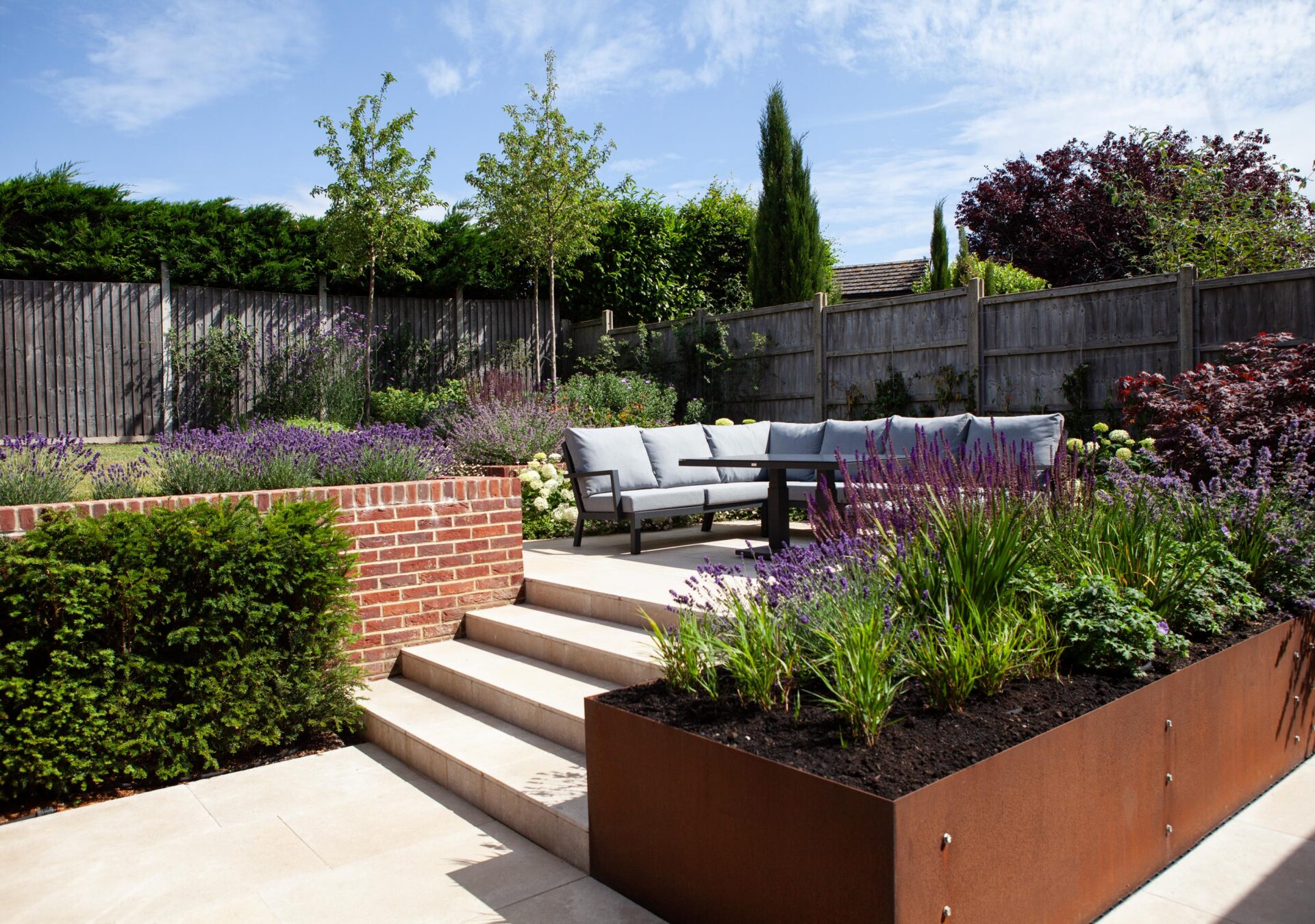 Contemporary landscaped garden with paved steps, raised planters, colourful planting and outdoor seating.